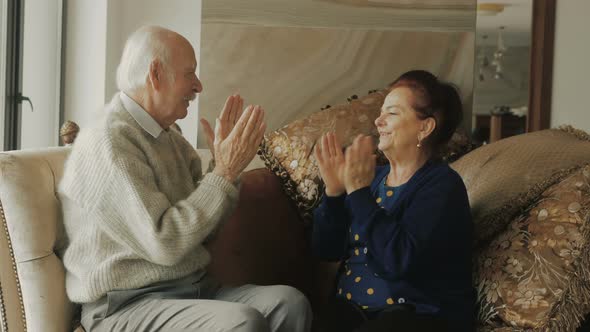 Happy elderly couple playing pat a cake. (Patting cake)
