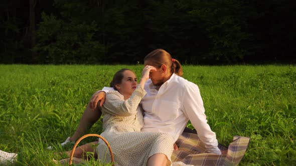 A Woman Lies on the Lap of a Man in Nature Romantically Straightens His Hair