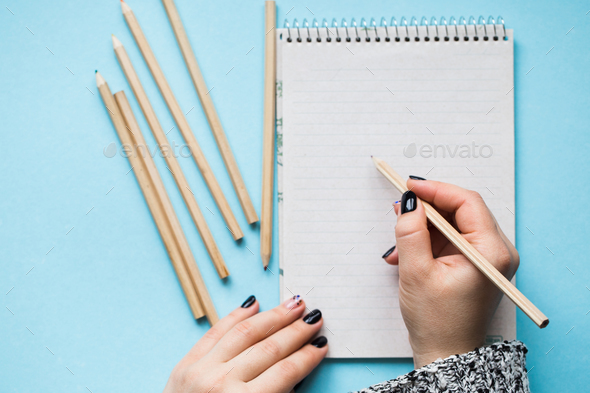 A woman with a beautiful manicure draws in a notebook