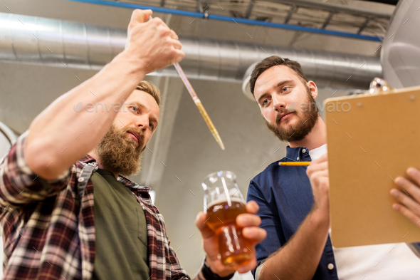 men with pipette testing craft beer at brewery - Stock Photo - Images