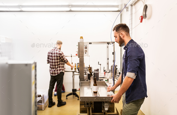 men with bottles on conveyor at craft beer brewery - Stock Photo - Images
