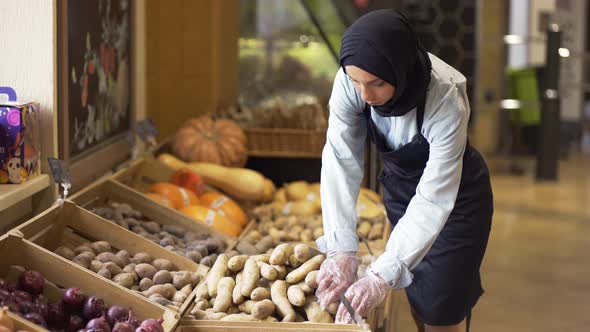 Woman in Hijab Refill the Potatos on the Stock at the Supermarket alt