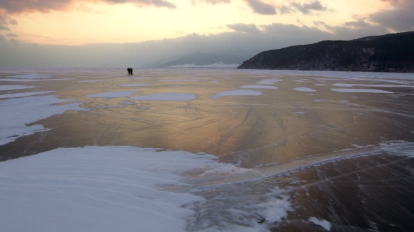 Man Are Skating on the Ice of Frozen Lake Baikal During Beautiful Sunset.