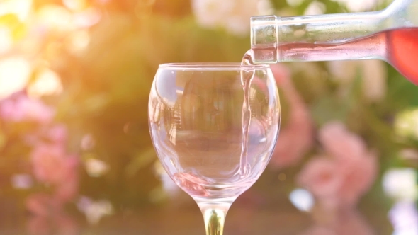 Waiter Pouring a Glass of Cold Rose Wine, Green Garden Background