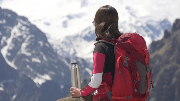 Woman Drinking Tea Form Thermos High in Mountains
