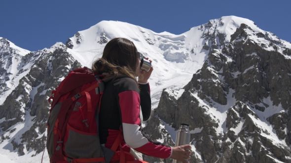 Woman Drinking Tea From Thermos on Top of Mountain