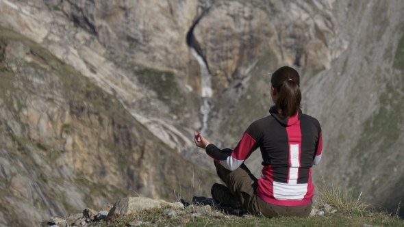 Woman in Lotus Pose Near Waterfall in Mountain