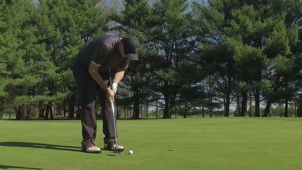 golfer putts the ball into the hole slow motion alt