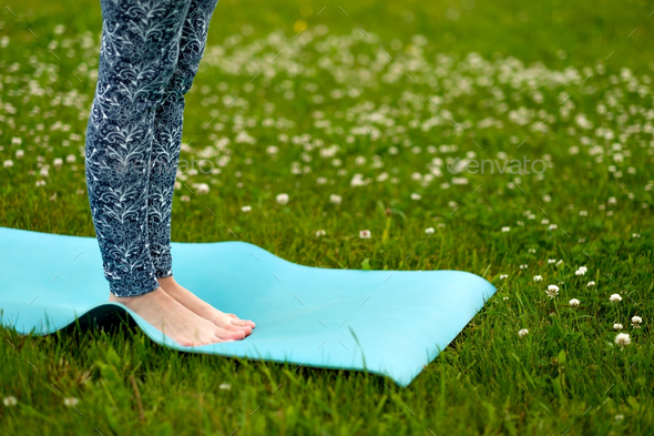 Young woman doing yoga exercise on green grass. face is not visible.