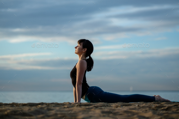 Yoga asana outdoors on beach. up facing dog pose