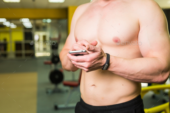 Muscular athlete checking training program on smartphone application
