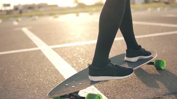 Closeup View of Woman's Legs in Black Sneakers and Long Socks Skateboarding on the Road in the City alt