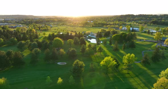 High rotating aerial shot of golf course. Country club green during spring sunset in America. alt