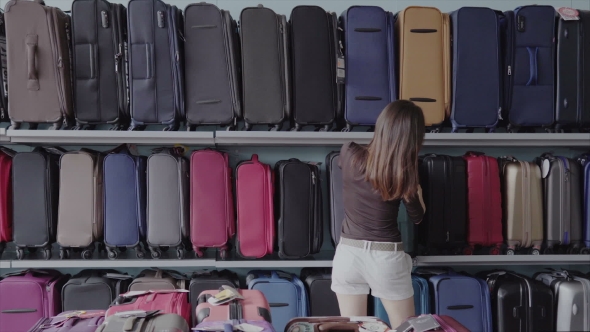 Woman Chooses Suitcase at Shop
