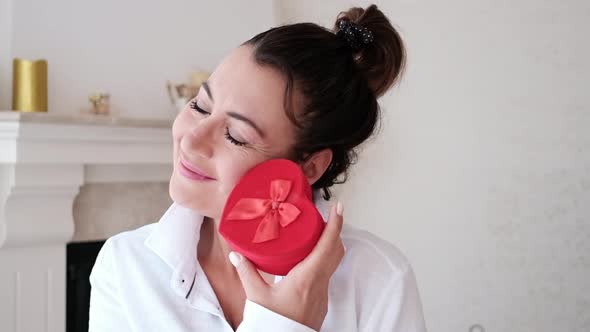 Woman holding red heart gift box and smiling