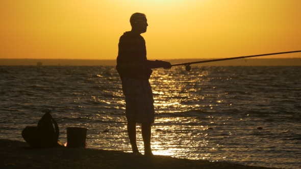 Man Fishing in Sea with Shining Water at Sunset