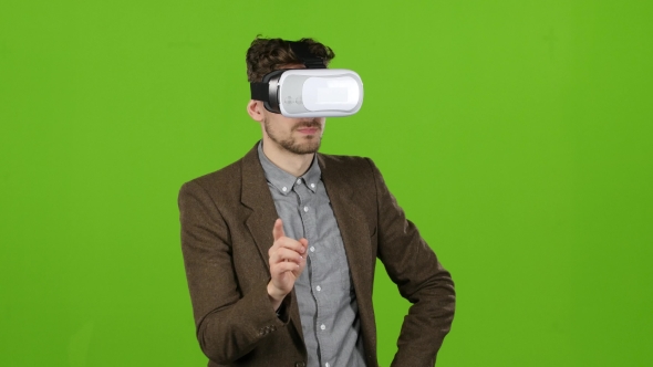 Boy in Virtual Glasses Looks at Imaginary Photographs and Smiles. Green Screen alt