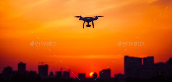 Modern Remote Control Air Drone Fly high with action camera in sunset sky