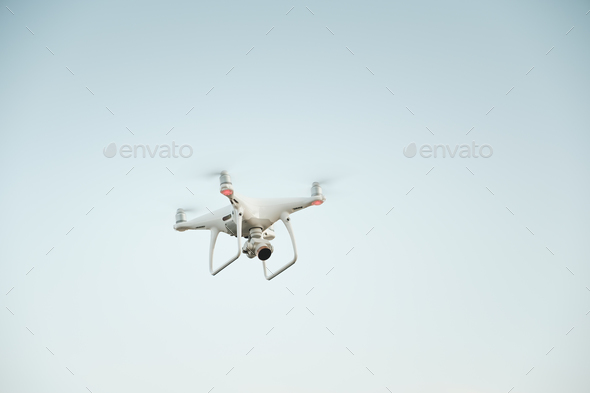 White drone hovering in a bright blue sky