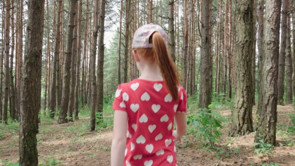 Little ginger girl walking through forest