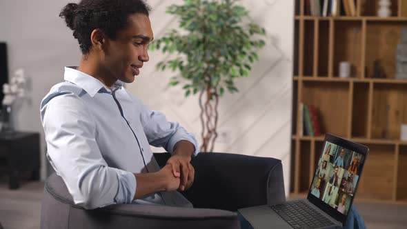 Side View of the Multiracial Young Guy Uses a Laptop for a Video Call at Home