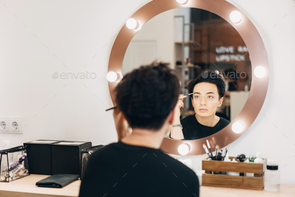 Attractive woman at the mirror in beauty studio - Stock Photo - Images