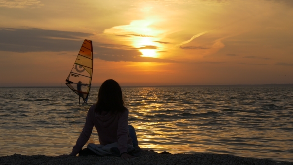 Woman Looking on Windsurfer at Sunrise