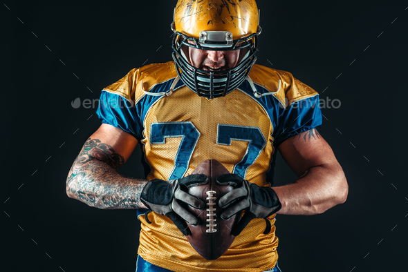 American football player holds ball in hands - Stock Photo - Images