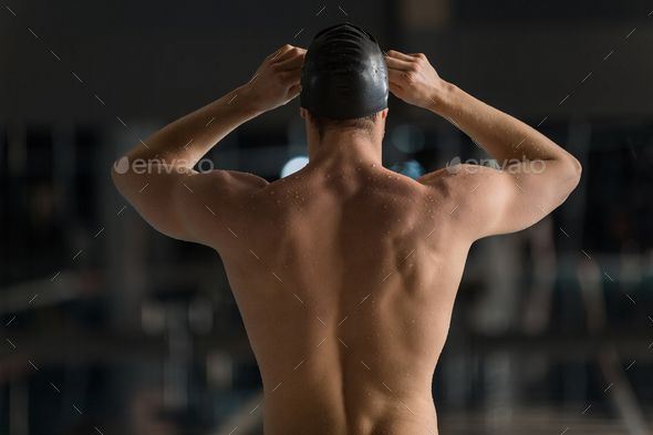Rear view of a male swimmer adjusting his goggles