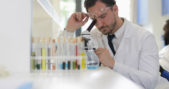 Man Scientist Working With Microscope In Laboratory Study Results Of Experiment alt