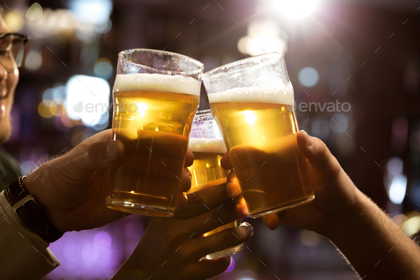 Men toasting with beer while sitting in pub together