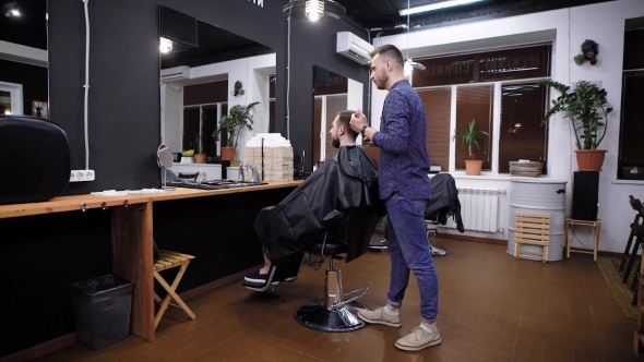 Side View of Master Combing Hair To Male Customer in Barber Shop alt