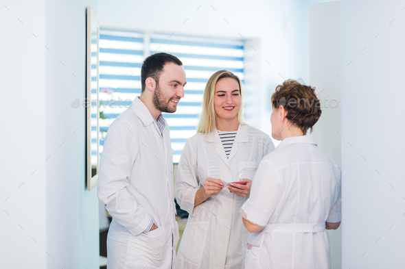 Mature doctor discussing with nurses in a hallway hospital. Doctor discussing patient case status - Stock Photo - Images
