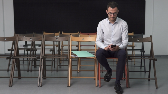 Business Man in Empty Conference Room Touching Smartphone
