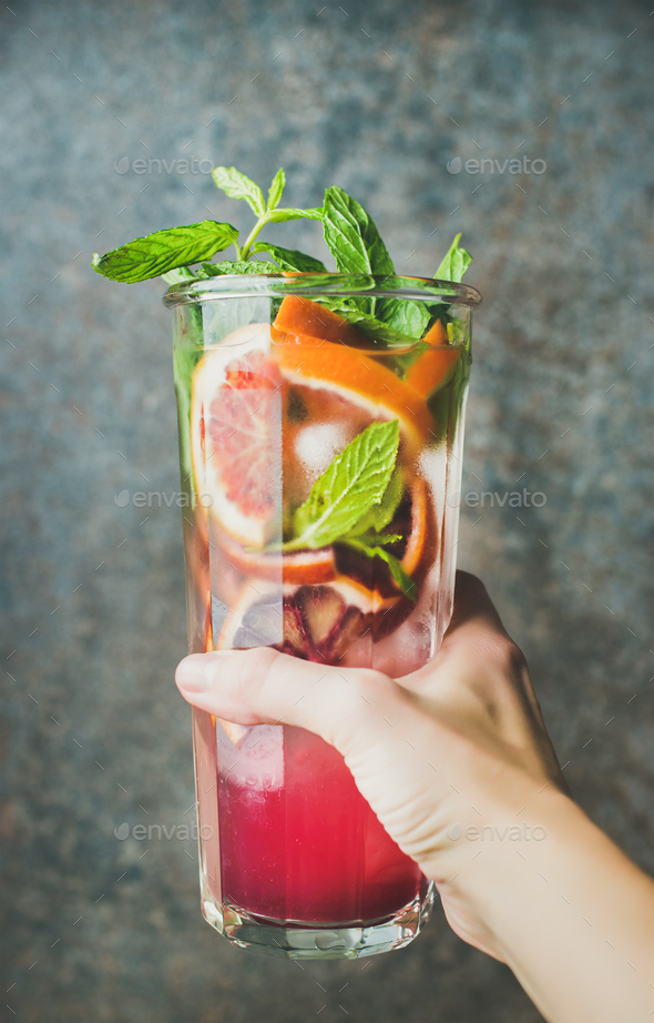 Woman's hand holding glass of homemade blood orange citrus lemonade - Stock Photo - Images