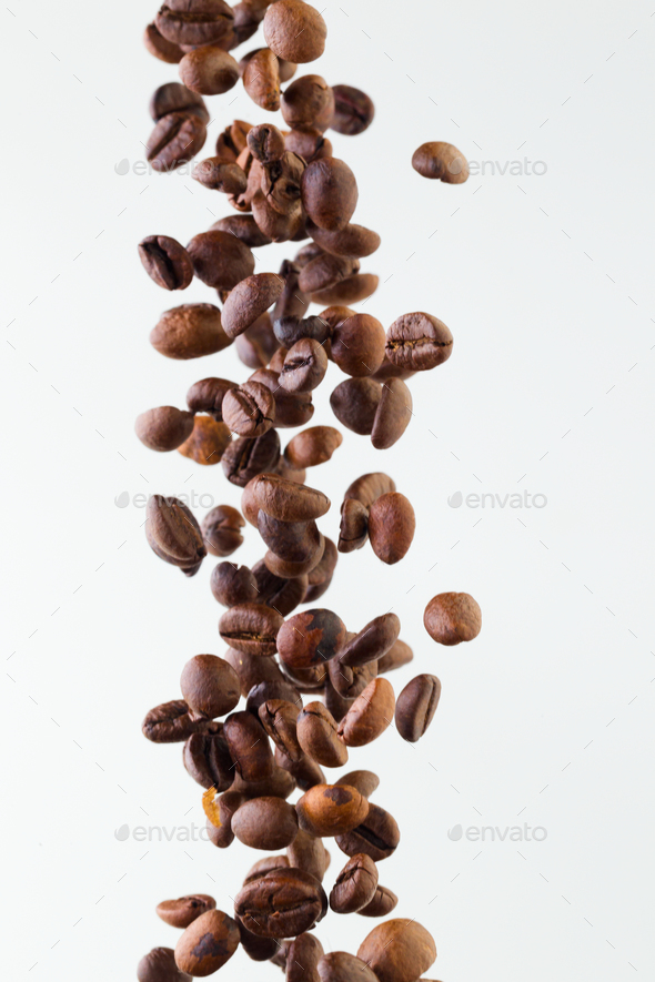 Falling grains of roasted coffee on a white background