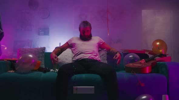 Bearded Man Sitting on Sofa During Party alt