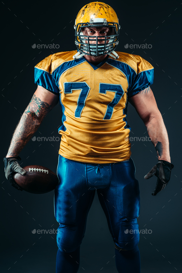 American football player holds ball in hands - Stock Photo - Images