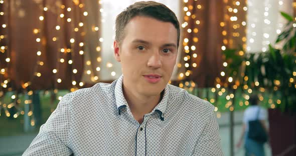 Cheerful Guy Takes Off Surgical Mask Against Blurred Lights alt