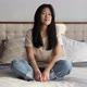 Attractive Smiling Asian Woman in Casual Clothes Sitting on the Bed at Home - VideoHive Item for Sale