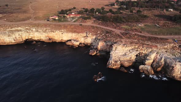 Drone top down aerial view of waves splash against rocky seashore, background. Flight over high clif alt
