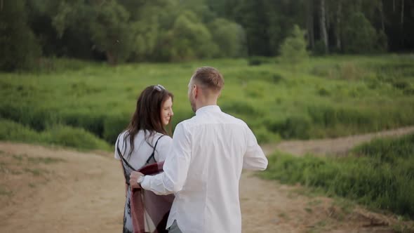 The Man Wraps the Girl in a Blanket While Walking in the Park in the Evening