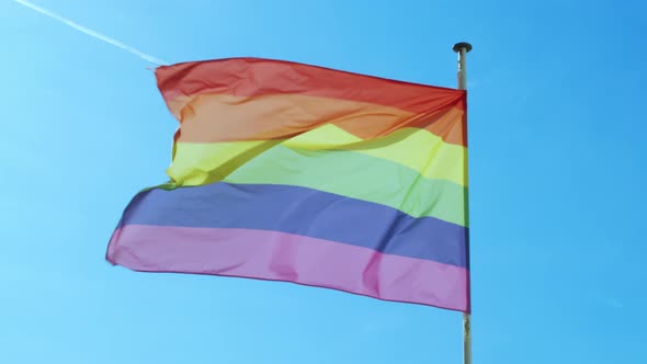 Big Rainbow Flag Gay Pride LGBTQ Developing By the Wind Against the Blue Sky alt