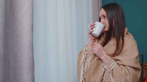 Young Adult Brunette Woman in Warm White Sweater Drink Hot Beverage Mug Relaxing at Home Near Window alt