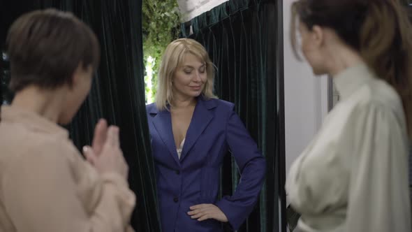 Confident Woman Opening Curtain in Dressing Room and Posing in Elegant Costume. Friends Showing alt
