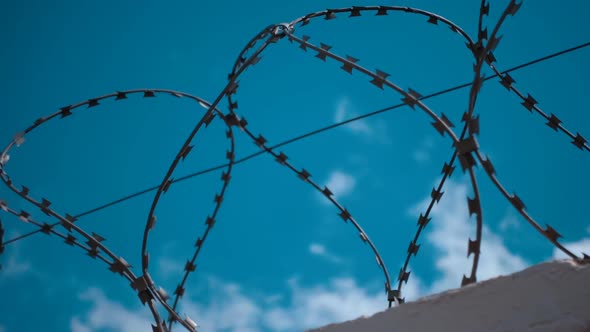 Barbed Wire At The Top Of Fence Against The Blue Sky With Clouds 3