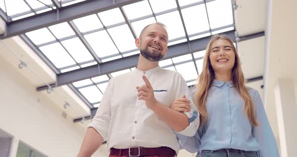 Beautiful Young Couple Walking and Talking on a Shopping Center Holding Hands alt