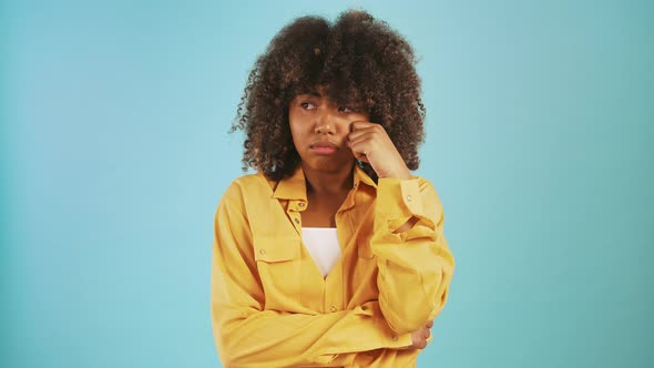 Young Darkskinned Woman Acting Like Crying Propping Her Face By Hands While Posing Against Blue alt