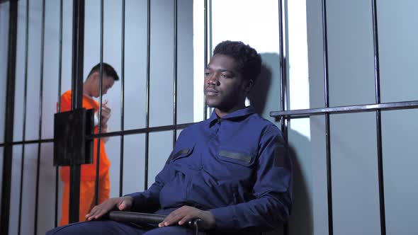 Black Jailer Sits in the Prison Corridor alt