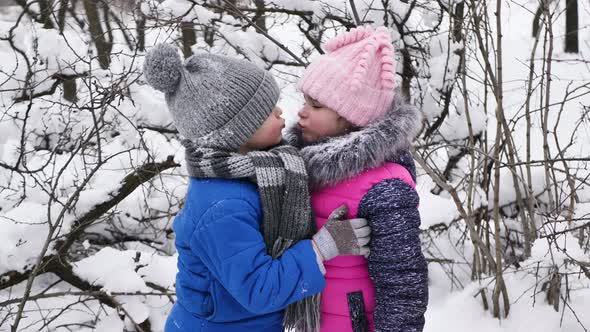 Children a Boy and a Girl Hug and Kiss in the Winter in the Cold in the Snowcovered Forest